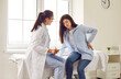 Pregnant woman feeling unwell suffering from backache during meeting with her gynecologist doctor in clinic. Female obstetrician consulting expectant girl sitting on the couch in office.