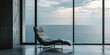 Modern lounge chair by a large window overlooking the sea.