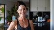 © irissca - Smiling Fit Woman Ready for New Years Fitness Goals. Cheerful and fit woman in workout attire stands in kitchen, motivated to start her New Years resolutions for health and fitness.