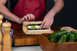 Close up of sushi chef hands making Japanese food. Man cooking sushi at restaurant or at home. Traditional asian rolls on cutting board. Maki sushi with cheese and vegetables: pepper and avocado