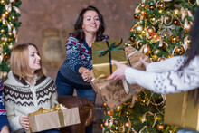 Happy Women Surprising Each Other With Christmas Gift Near Decorated Christmas Tree