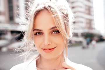 Closeup portrait of young beautiful smiling woman. Sexy carefree model posing on the street background at sunset. Positive blond female. Cheerful and happy. Outdoors at sunny day. Blue eyes