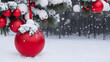 Image de Noël avec des boules de sapin rouge brillant avec des reflets, dans la neige, de petits flocons de neige tombant