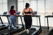 Rear view of two overweight Asian women in sports clothes. Wing exercises on the treadmill in the gym.
