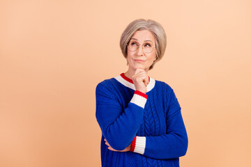 Poster - Portrait of charming minded lady wearing trendy blue clothes looking up hmm offer empty space isolated on beige color background