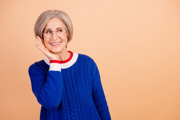 Sticker - Photo of senior woman with gray hair dressed knitwear warm sweater look empty space sale palm on cheek isolated on beige color background