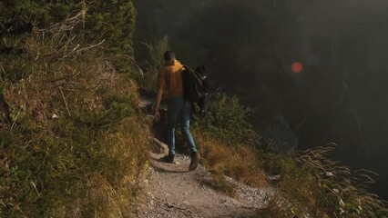 Wall Mural - Man traveler walks through the forest to the mountains. Incredibly beautiful views in the Alpine mountains. Hiking route in the Alps mountains in autumn