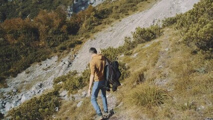 Wall Mural - Man traveler walks through the forest to the mountains. Incredibly beautiful views in the Alpine mountains. Hiking route in the Alps mountains in autumn