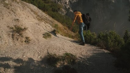Wall Mural - Man traveler walks through the forest to the mountains. Incredibly beautiful views in the Alpine mountains. Hiking route in the Alps mountains in autumn. Slow motion
