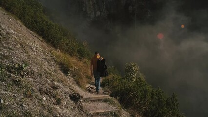 Wall Mural - Man traveler walks through the forest to the mountains. Incredibly beautiful views in the Alpine mountains. Hiking route in the Alps mountains in autumn. Slow motion