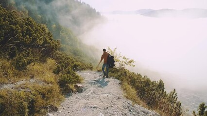 man traveler walks through the forest higher than clouds to the mountains. incredibly beautiful view