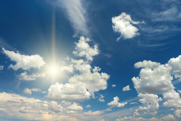 Sticker - Sun on beautiful blue sky with white fluffy clouds.