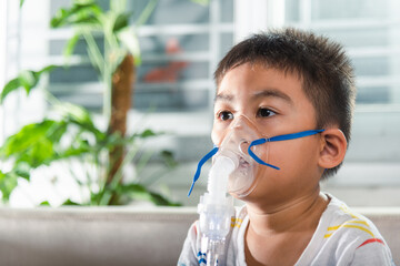 asian child using nebulizer mask equipment alone have smoke, kid boy making makes inhalation nebuliz