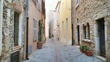 Young Woman Walking On The Streets Surrounded By Colorful Ancient Buildings In Antibes, France