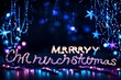 Sparkling Christmas lights in the evening at night on a dark background and the inscription Merry Christmas. Blue and purple color