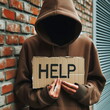 Hooded man holding a cardboard sign with the word help on it