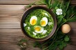 Top-down view of green sorrel and spinach soup with boiled egg and sour cream on rustic white table.