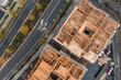 Top down aerial view over a construction site of apartment buildings with framing, concrete and workers wearing protective gear working on site.