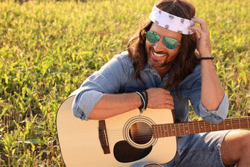 Canvas Print - Portrait of happy hippie man with guitar in field