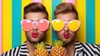 abstract composition of fruits and couple of gays in sunglasses on a bright yellow background