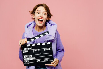 Poster - Young shocked woman wears purple vest sweatshirt casual clothes hold in hand classic black film making clapperboard isolated on plain pastel light pink background studio portrait. Lifestyle concept.