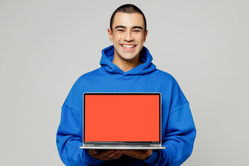 Wall Mural - Young middle eastern man wear blue hoody casual clothes hold use work on laptop pc computer with blank screen workspace area isolated on plain solid white background studio portrait Lifestyle concept