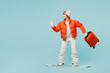 Traveler woman she wear padded windbreaker jacket ski goggles mask hold suitcase bag snowboard isolated on plain blue background. Tourist travel abroad in free time rest getaway. Air flight concept.