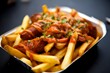 Savory fries topped with hotdog slices drizzled with ketchup, garnished with herbs.