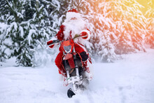 Biker Santa Claus Fast Delivering Christmas Gifts On Snow Bike, Motorcycle Ski Background Snow Forest, Sunlight