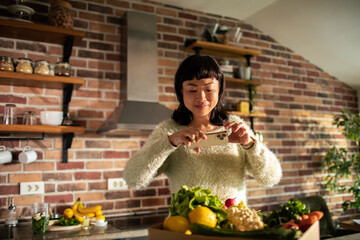 Smiling woman taking a photo of healthy vegetables in a cozy kitchen setting