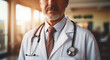 Middle-aged male doctor in white lab coat with stethoscope against the backdrop of a blurry clinic in daylight. Healthcare, medical staff concept