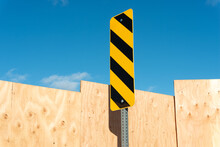 Traffic Sign With Black And Yellow Caution Stripes, Plywood Hoarding, And Blue Sky