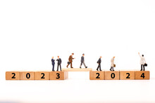 Miniature Figure Businessman  Walking On Number Wooden Block Across From 2023 To 2024 New Year