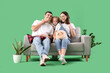 © Pixel-Shot - Happy family with dog sitting on sofa against green background