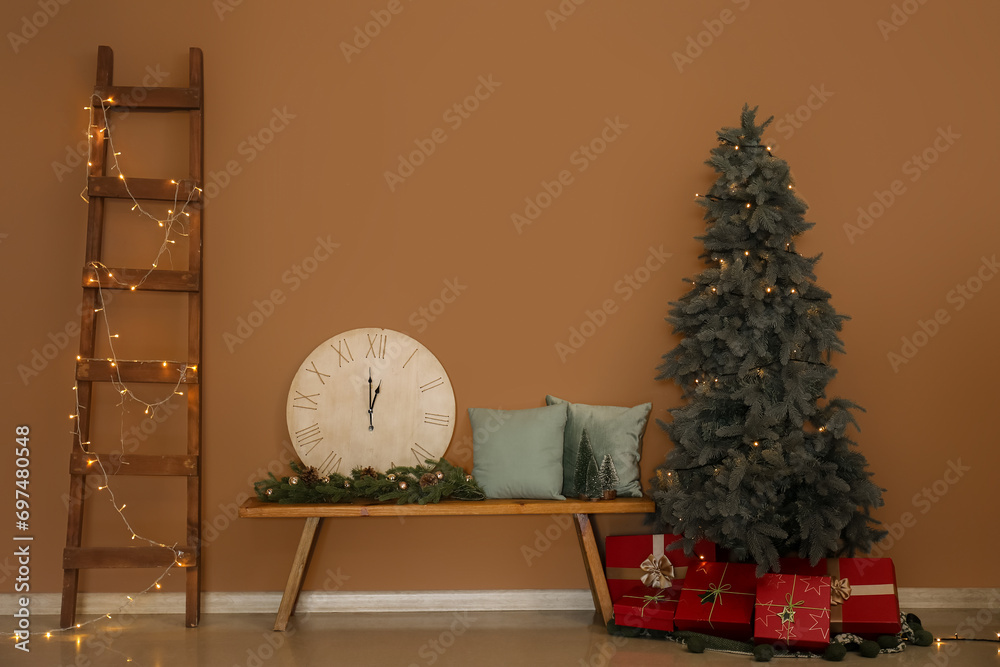 Beautiful decorated Christmas tree with big clock on bench near beige wall
