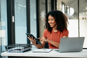 Young woman typing on tablet and laptop while sitting at the working in office