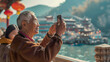 An elderly Chinese tourist man using a smartphone to take photos of the scenery.