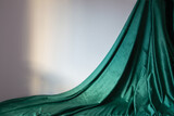 Fototapeta  - green velvet curtain and gray wall in sunlight