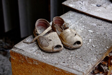 Dusty Sandals With Holes And A Broken Strap On A Ledge.
