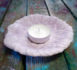 Concrete light pink leaf-shaped candlestick with white tea candle. Handiwork. Mobile photo.