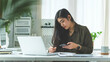 © wattana - Beautiful asian businesswoman sitting at her workplace and using smart phone.