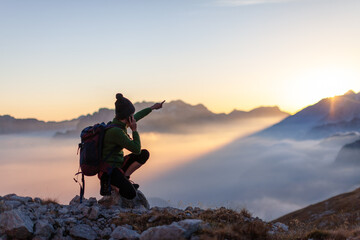 woman tourist talking on her phone from remote locations in high mountains and with her hand showing