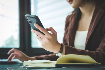 Cropped image of young woman in business suit using smart phone. Copy space for your text.