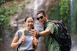 © wattana - Happy young couple taking selfie with smartphone in front of tropical waterfalls in summer vacation.