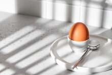 Boiled Egg In Hard Light With Window Shadows On White Kitchen Background. Light Protein Breakfast Concept, Minimalism, High Key