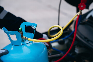 Close up hand of Mechanics inspect and check the refrigerant and fill the car air conditioner. Worker service car air conditioner.	