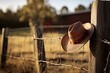 A Symbolic Embrace of the Frontier: A cowboy hat and lasso adorn a wooden fence, embodying the timeless essence of ranch life and the rugged spirit of the Wild West.