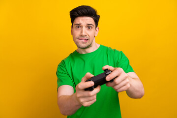 Photo portrait of attractive young brunet man play station nervous dressed stylish green clothes isolated on yellow color background