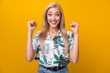 Wall Mural - Photo of overjoyed ecstatic girl with long hairdo dressed shirt clenching fists shout supporting you isolated on yellow color background