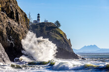 King Tides At Cape Disappointment Stae Part. Large Waves Crashing On A Cliff With A Lighthouse In A Background